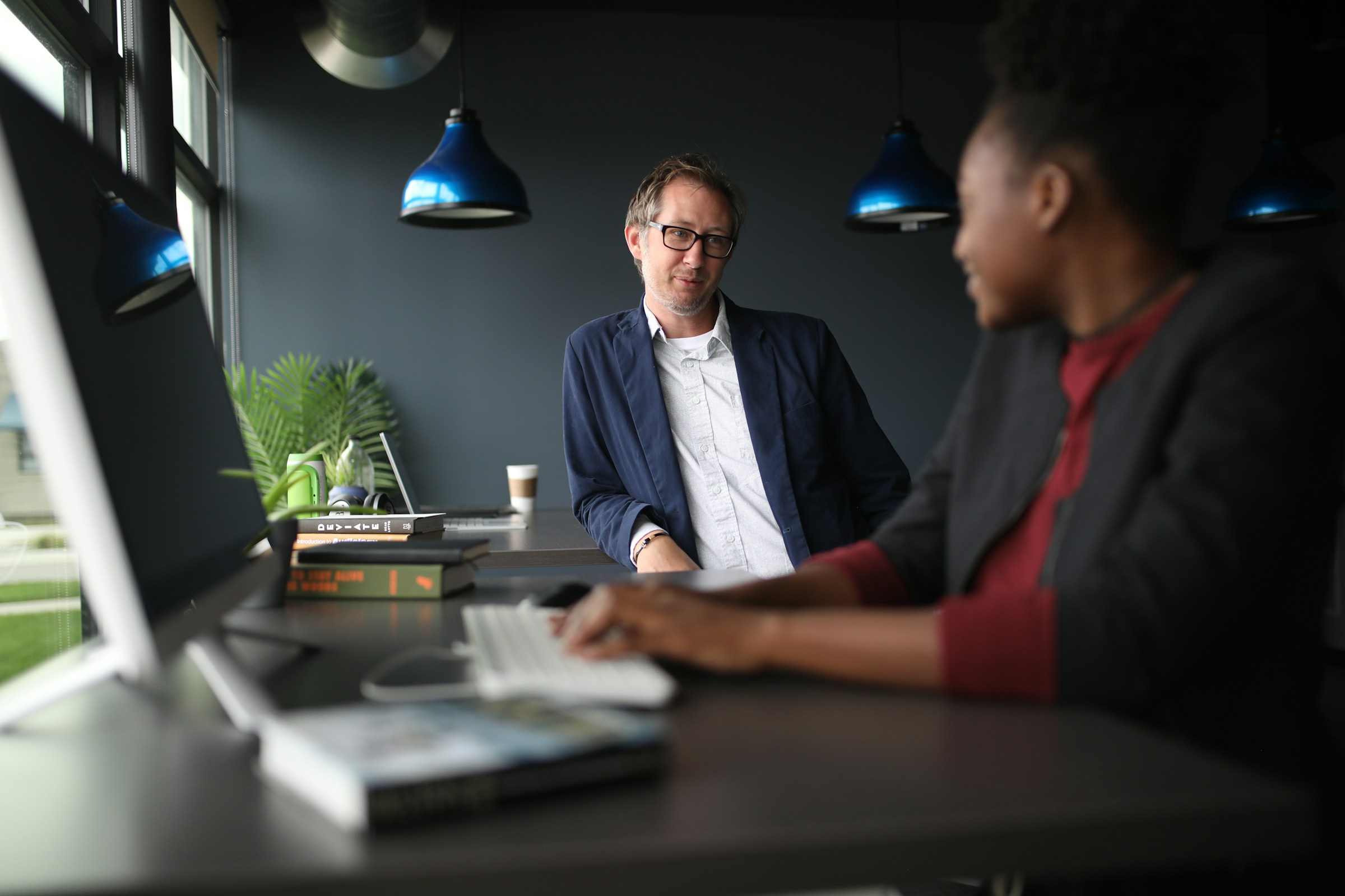 Two colleagues talking at a standing desk in a modern office